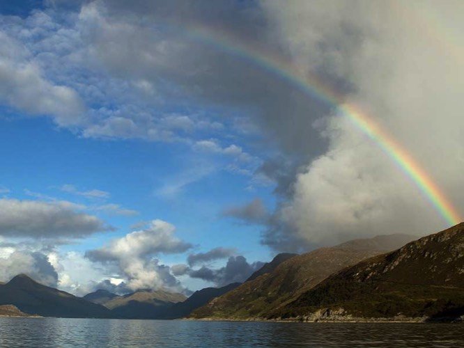 Uitzicht over een loch met een regenboog