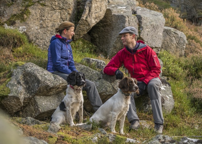 Twee wandelaars en hun honden genieten van een ruspauze tijdens een wandeling in het Cairngorms National Park.